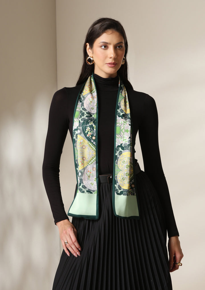 Woman wearing a botanical paisley silk scarf styled over a black turtleneck and pleated skirt