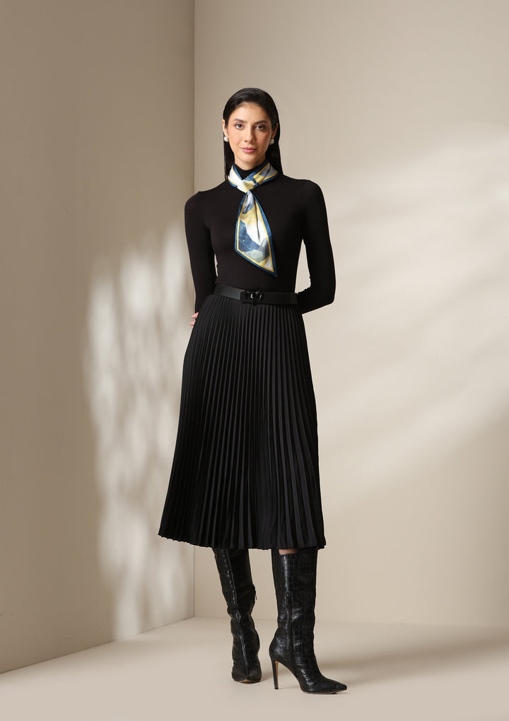 Woman wearing a multicolour abstract silk scarf styled around the neck with a black turtleneck and pleated skirt