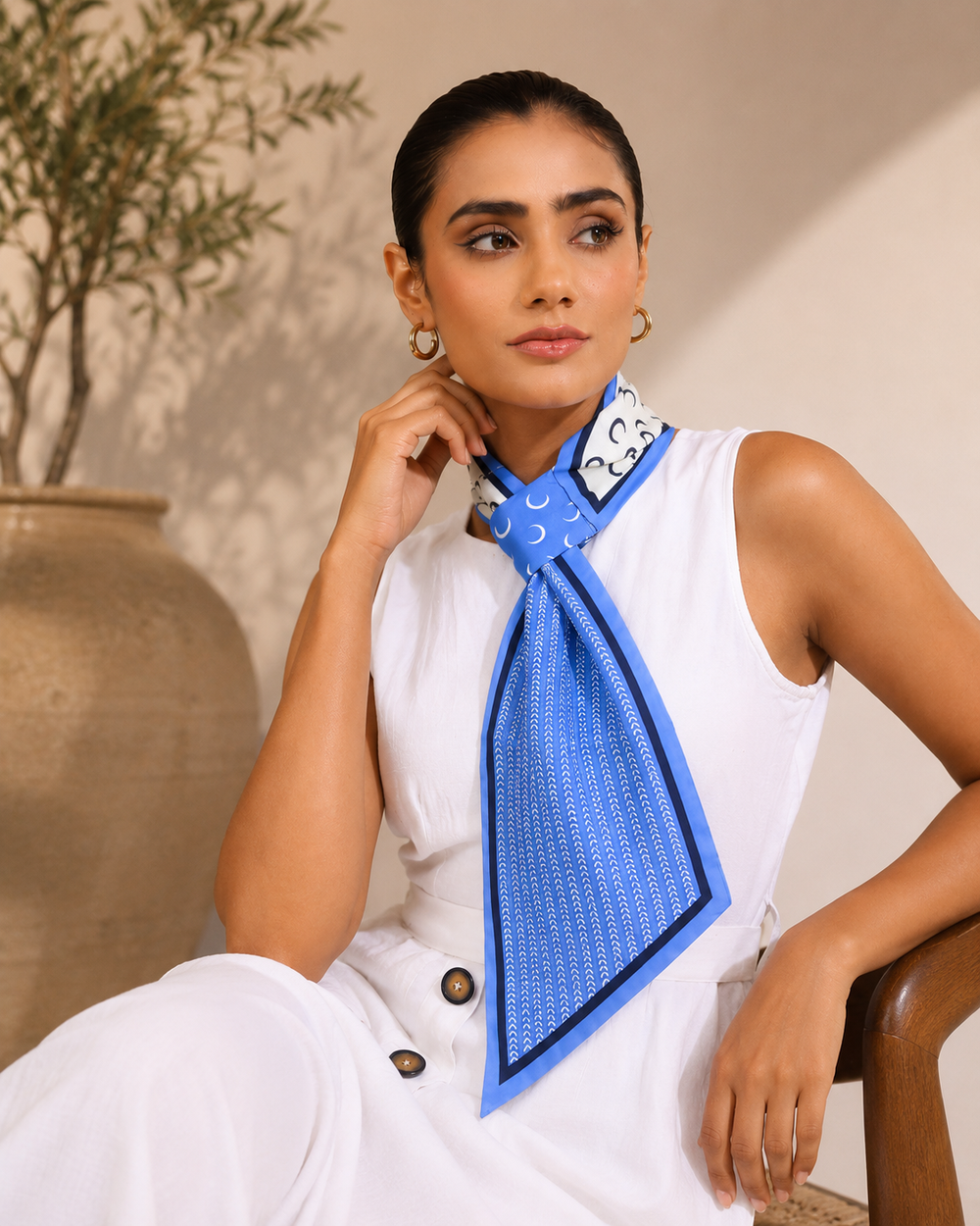 Woman wearing a blue silk neck scarf with ivory print and navy border styled with a white sleeveless top